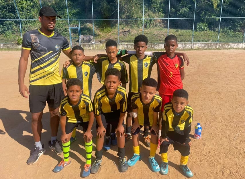 Time de uniforme amarelo e preto posando com o técnico