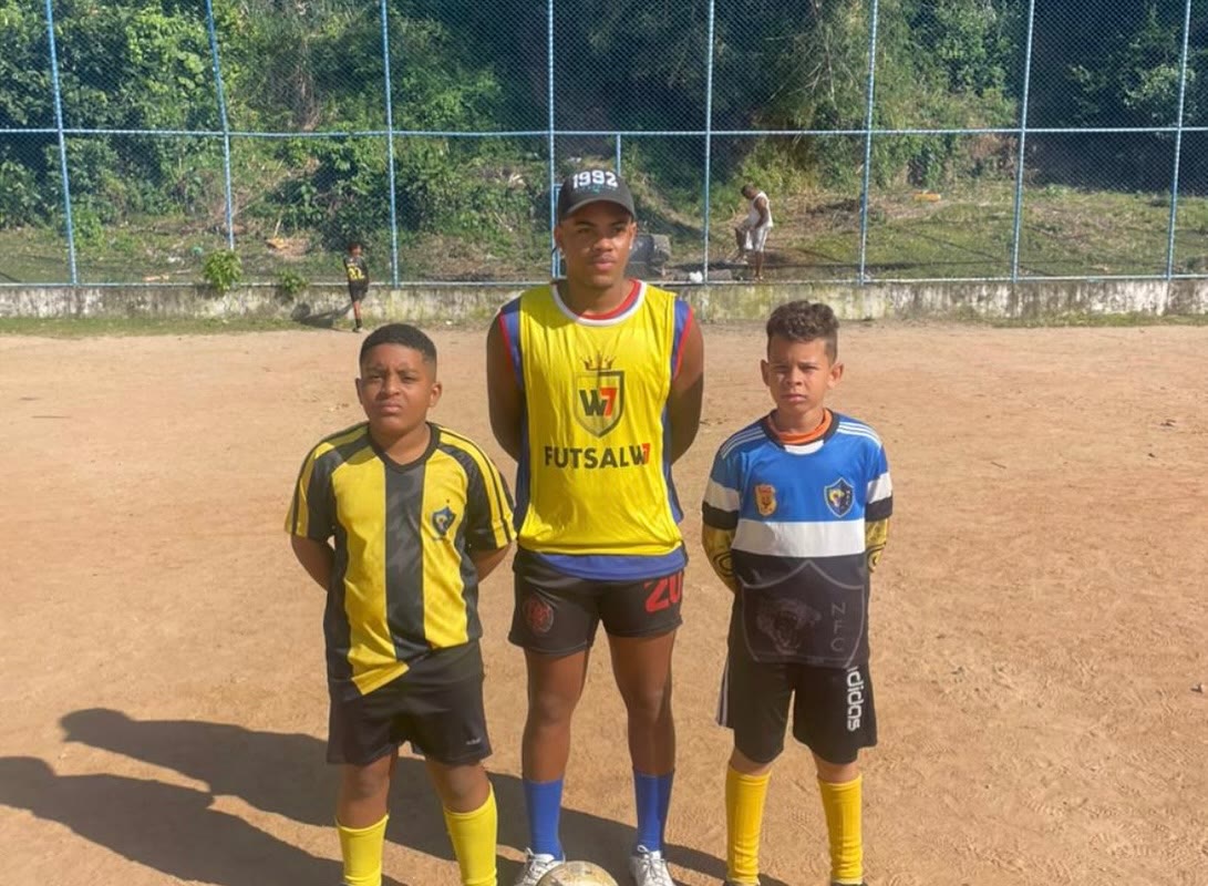 Dois jogadores e um professor de futsal no campo